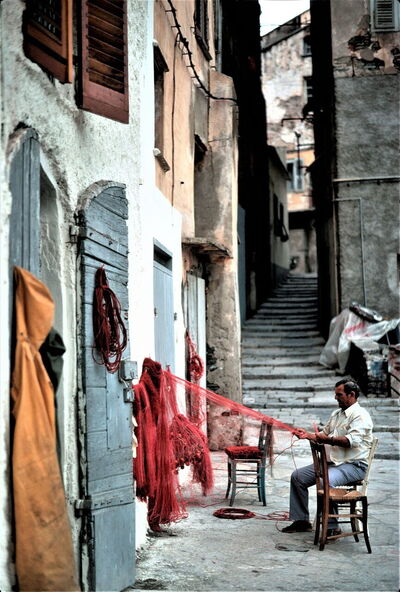Man repareert een visnet op Corsica